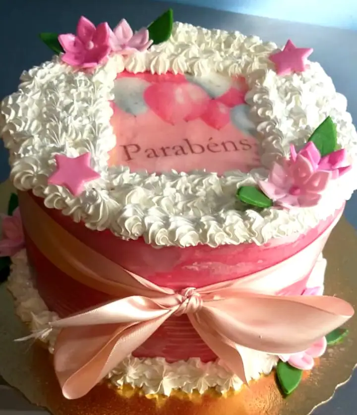Bolo com papel de arroz de parabéns e laço rosa
