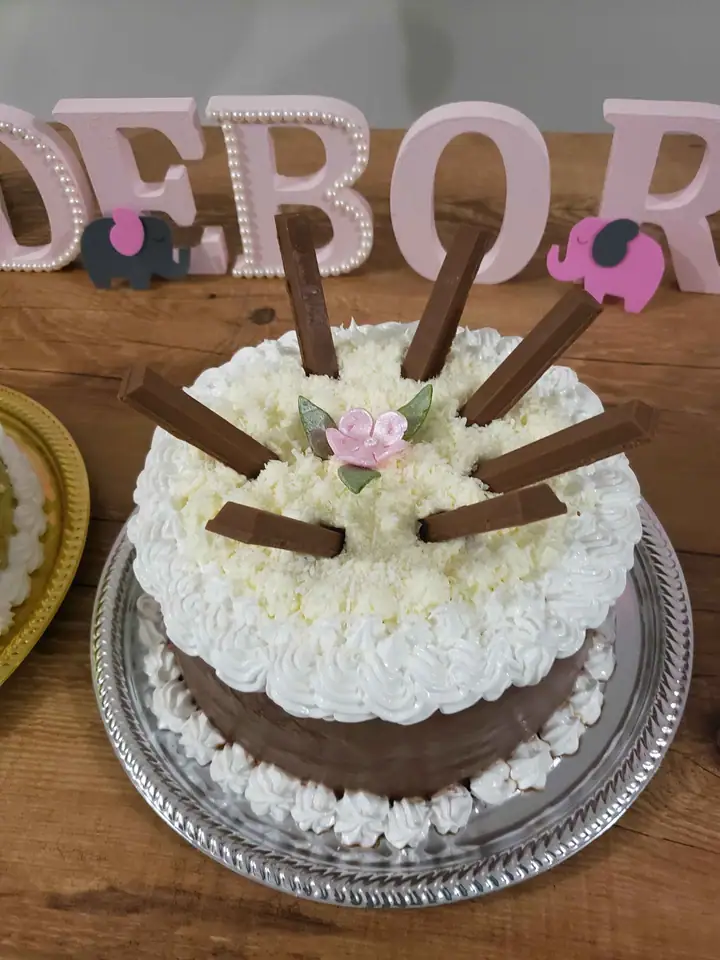 Bolo de merengue branco com barras de chocolate e flor rosa