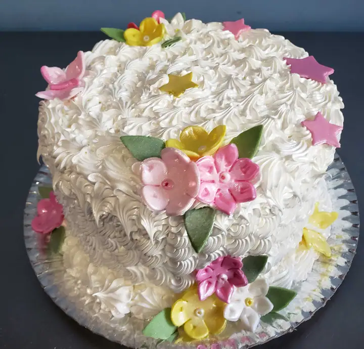 Bolo de merengue branco com flores coloridas e estrelas