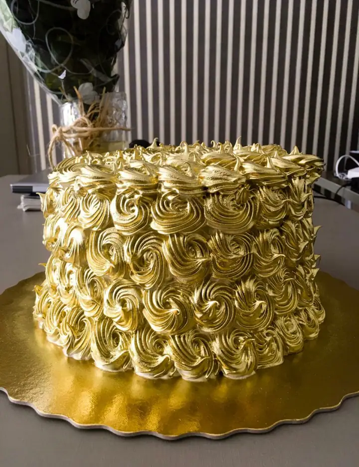 Bolo alto coberto de rosetas de merengue dourado