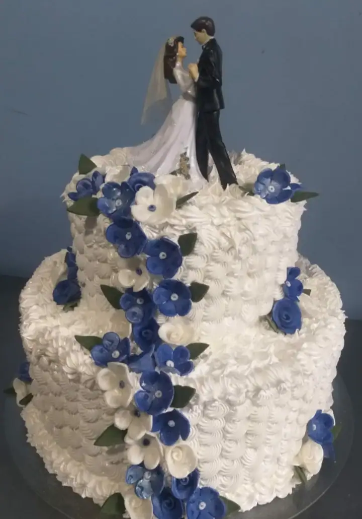 Bolo de casamento de dois andares com flores azuis e noivinhos