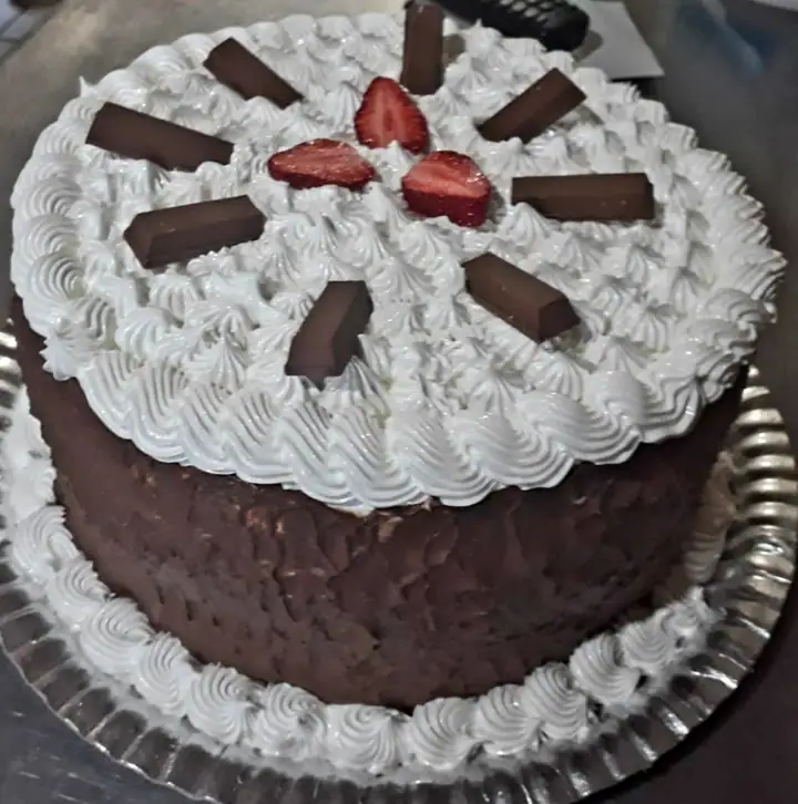 Bolo de chocolate com merengue branco, morangos e barras de chocolate