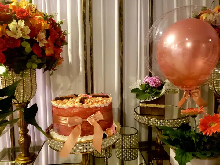 Bolo com laço de fita sobre mesa de festa decorada