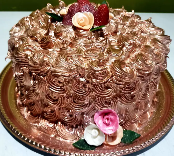 Bolo redondo com merengue cor de cobre em espirais, morangos e rosas de açúcar