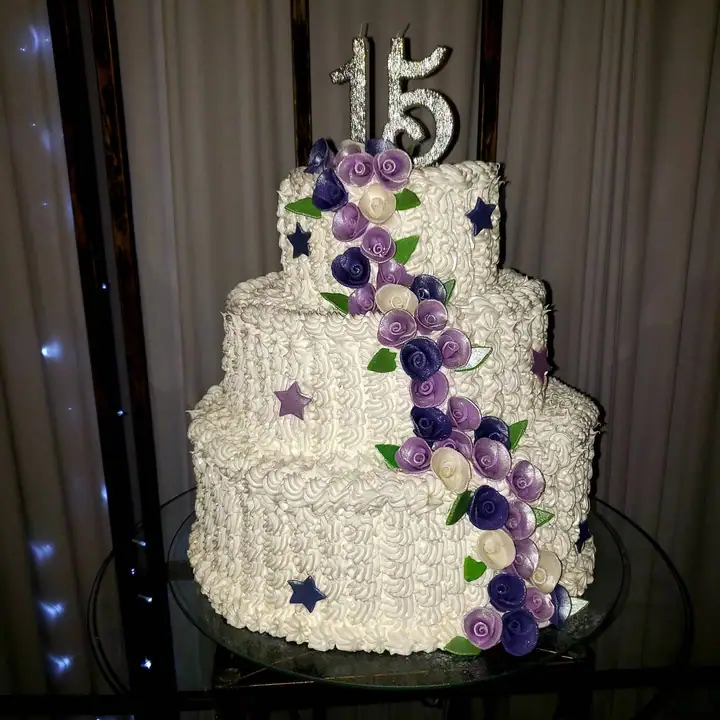 Bolo de três andares branco com cascata de rosas lilás e topo de 15 anos